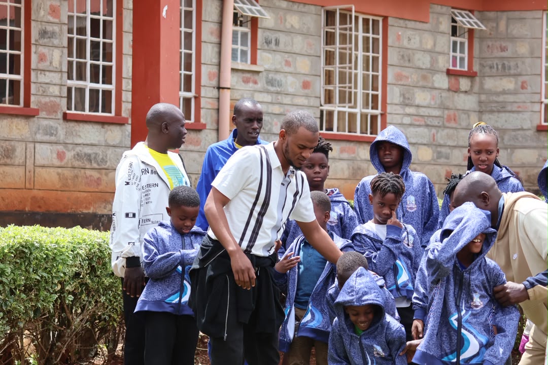 Academy coach speaking with a large group of players outside a school building